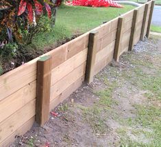 a wooden planter filled with lots of plants next to a tree and grass field