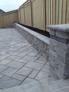 an outdoor patio with stone walls and brick paversed walkways in the foreground