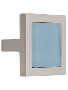 a light blue glass door handle on a white wall with a square frame in the middle