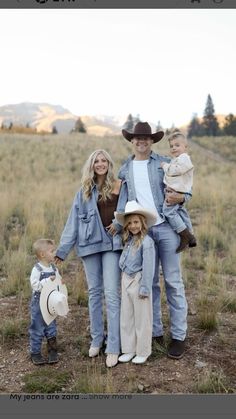 a man, woman and two children posing for a photo in the grass with mountains in the background