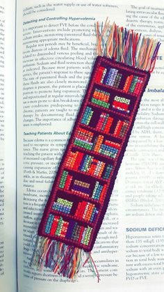 an open book with a colorful piece of art on it's cover and some tassels