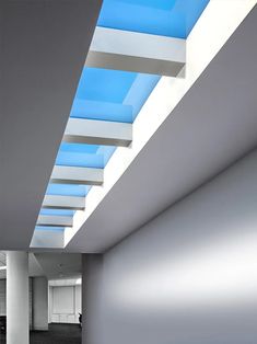 an empty room with white walls and blue skylights on the ceiling is lit by daylight