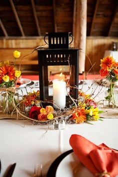 a candle is lit on top of a table with orange and yellow flowers in the center