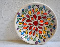 a white plate with multicolored designs on the outside and inside, sitting on a table