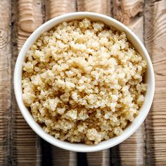 a white bowl filled with rice sitting on top of a wooden table