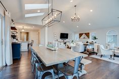 a large open concept living room and dining room area with wood flooring, white walls and ceiling lighting