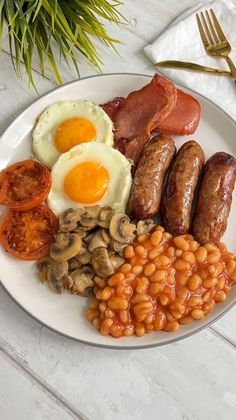 a white plate topped with eggs, sausages and beans