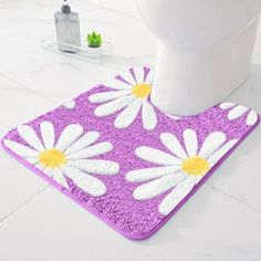 a white toilet sitting next to a purple and yellow flowered rug on top of a bathroom floor