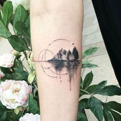 a person with a tattoo on their arm that has mountains and trees in the background