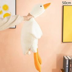 a stuffed duck hanging from the side of a wall next to a book shelf with books on it