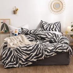 a zebra print comforter set on a bed with pillows and throw blankets in the corner