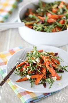 a salad with carrots and cranberries on a white plate