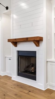 an empty room with a fireplace and white walls