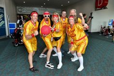 a group of people dressed in yellow and red posing for a photo with a ball