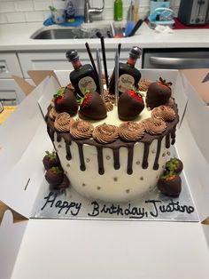 a birthday cake with chocolate frosting and strawberries on the top is in a box