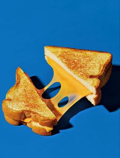 a grilled cheese sandwich cut in half on a blue background with a bite taken out