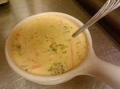 a white bowl filled with soup on top of a metal counter next to a spoon