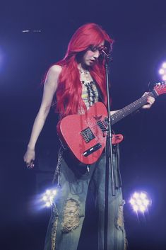 a woman with red hair holding a guitar