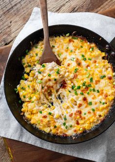 a skillet filled with macaroni and cheese on top of a wooden table