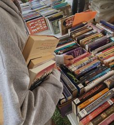 a person standing in front of a table full of books