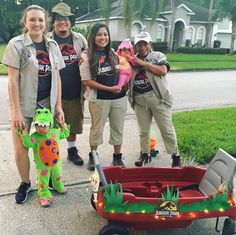 a group of people standing next to each other in front of a red wagon filled with toys