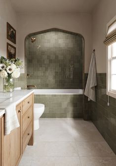 a bath room with a toilet a sink and a bath tub next to a window