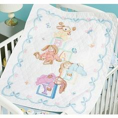 a baby crib with a teddy bear blanket on it's side and a lamp next to the crib