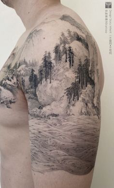 a man's back with a mountain scene tattoo on his arm and shoulder, in black and white