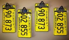 three yellow license plates hanging on the wall next to each other, with numbers printed on them