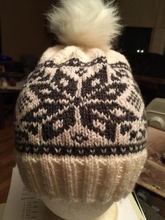 a white and black knitted hat sitting on top of a mannequin's head