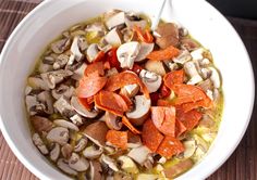 a bowl of soup with mushrooms, carrots and broth