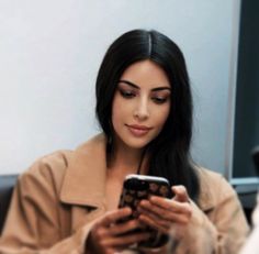 a woman sitting at a table looking at her cell phone