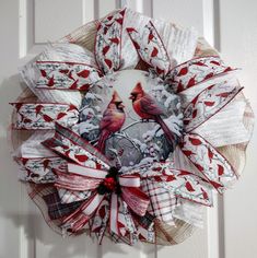 a red and white wreath with two cardinals on it