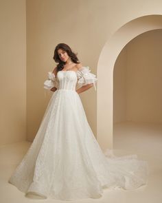 a woman in a white wedding dress standing next to an arched doorway with her hands on her hips