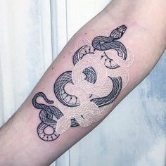 a tattoo on the arm of a person that has a snake and two snakes in it