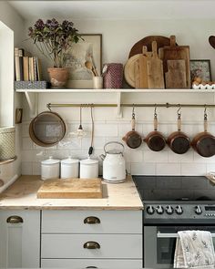 a kitchen with pots and pans on the shelves above the stove, along with other cooking utensils