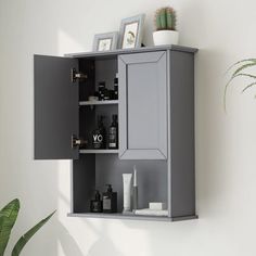 a gray cabinet with two doors on the wall next to a potted green plant