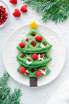 a christmas tree made out of pancakes on a plate with raspberries around it