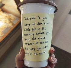 a person holding up a coffee cup with writing on it