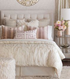 a bedroom with a bed, nightstands and mirror on the wall above it is decorated in neutral colors