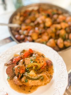 a white plate topped with food next to a skillet filled with meat and veggies