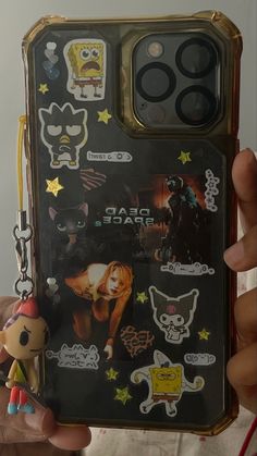 a person holding up a cell phone case with stickers on it