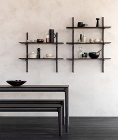 a table with two benches in front of it and shelves on the wall behind it