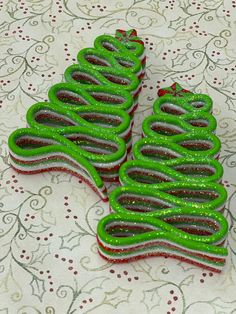 two green christmas trees sitting on top of a white tablecloth covered table next to each other