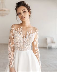 a woman in a white wedding dress with long sleeves and an open back is posing for the camera