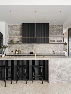 a kitchen with marble counter tops and black bar stools