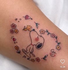 a person with a tattoo on their leg that has a dog and flowers around it