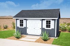 a small gray and white shed sitting in the grass