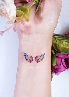 a woman's wrist with an angel wing tattoo on the left side of her arm