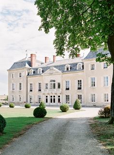 a large white building sitting next to a lush green field